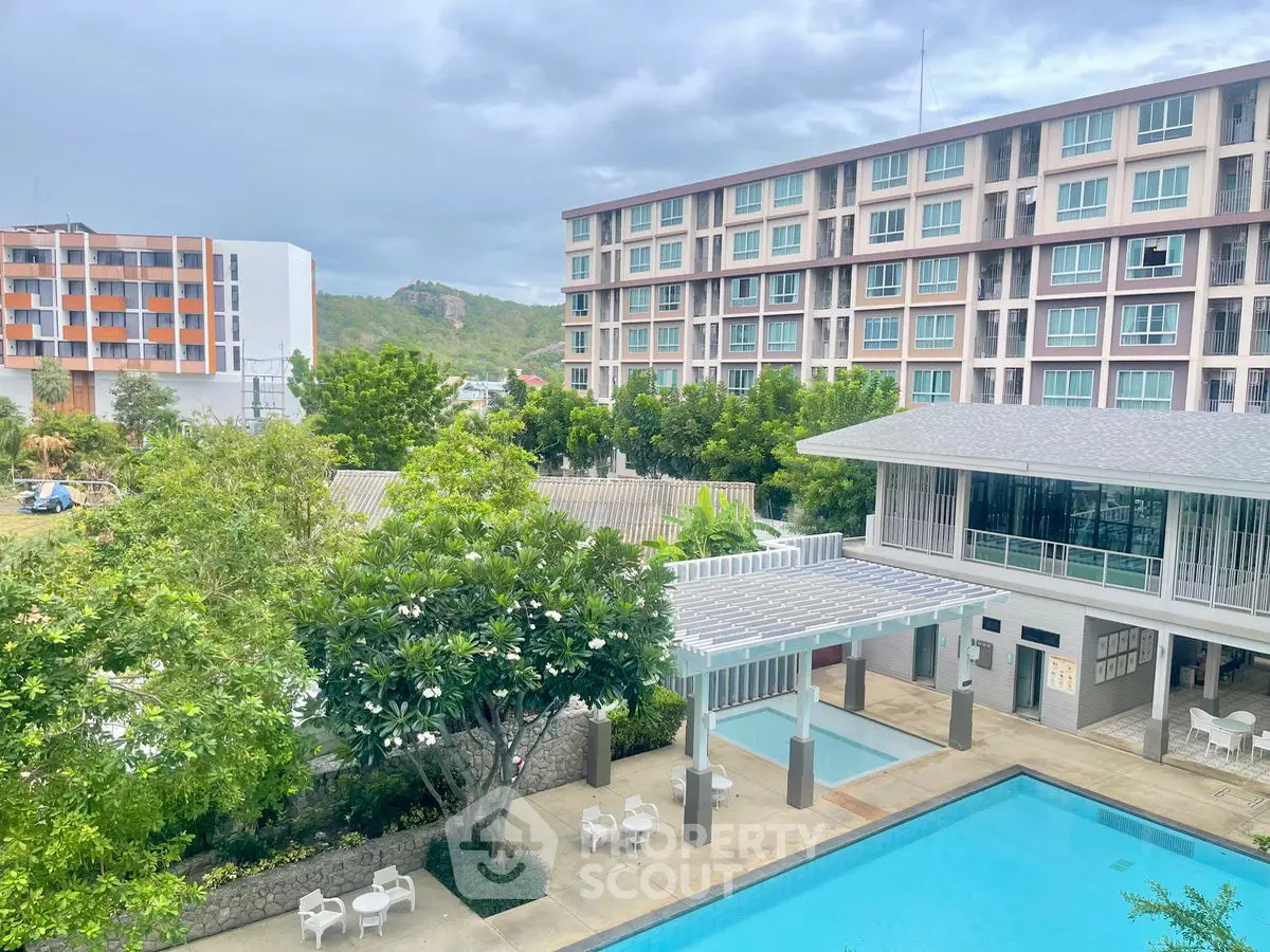 Modern apartment complex with pool and lush greenery, offering serene living environment.
