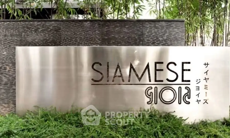 Elegant entrance sign of Siamese Gioia surrounded by lush greenery and modern design elements.