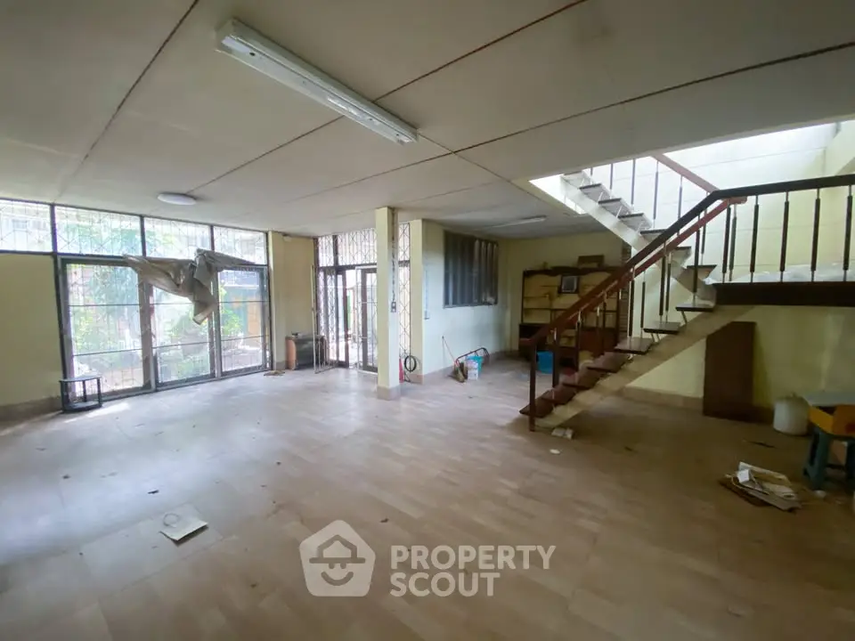 Spacious open-plan living area with large windows and staircase, ideal for customization.