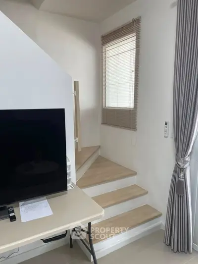 Modern interior with sleek staircase and TV setup, perfect for contemporary living.