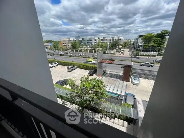Modern urban view from a balcony overlooking a busy street and contemporary buildings.