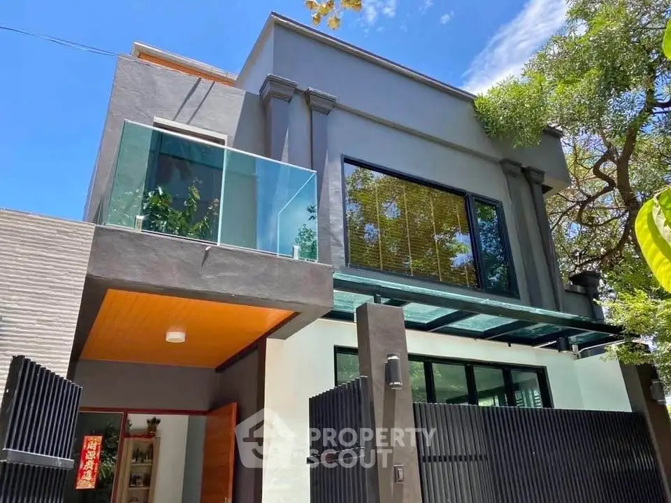 Modern two-story house with glass balcony and sleek design.
