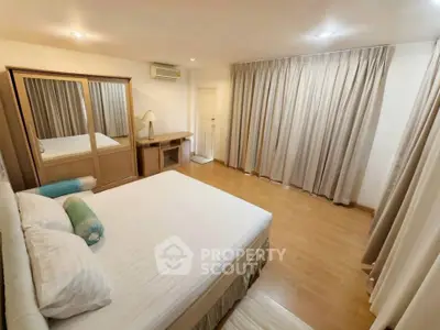 Spacious bedroom with wooden flooring and elegant curtains in a modern apartment.