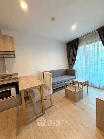 Modern living room with cozy sofa, dining table, and kitchenette in bright apartment.