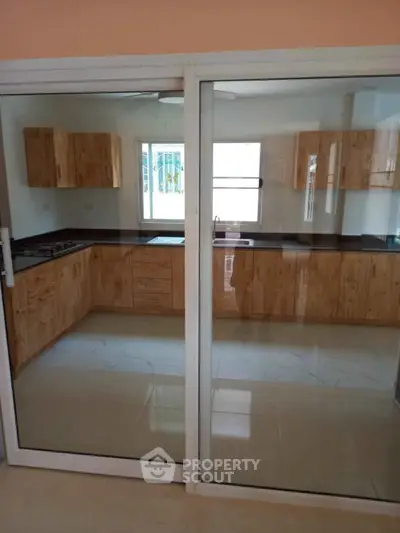 Modern kitchen with wooden cabinets and glass sliding doors in a spacious layout.
