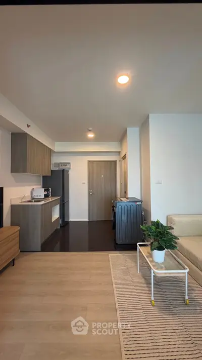 Modern open-plan living room with kitchen, featuring sleek cabinetry and cozy seating area.
