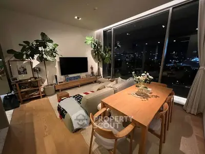 Modern living room with large windows and city view, featuring cozy seating and dining area.