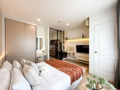 Modern bedroom with cozy decor and open layout, featuring a stylish bed, built-in storage, and a compact kitchen area.