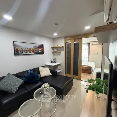 Modern living room with sleek furniture and open view to bedroom