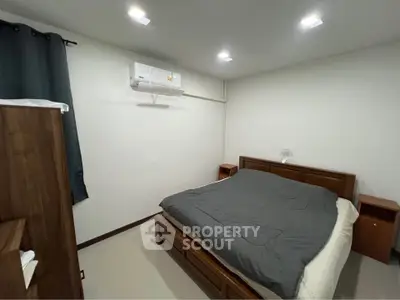 Cozy bedroom with modern air conditioning and wooden furniture