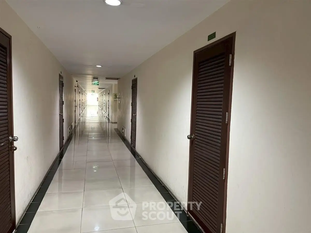 Spacious and well-lit corridor in a modern apartment building with multiple doors.