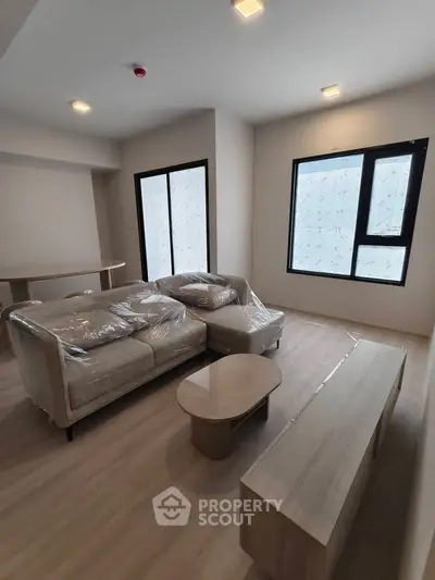 Modern living room with sleek furniture and large windows in a new apartment.
