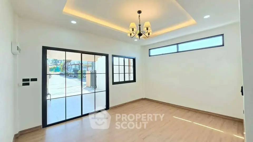 Spacious living room with elegant chandelier and large windows for natural light.