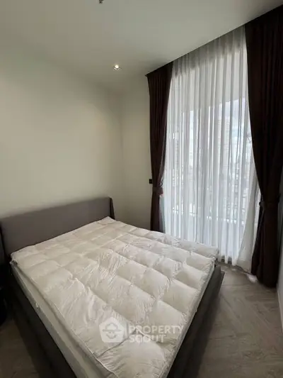 Cozy bedroom with large window and elegant curtains in modern apartment.