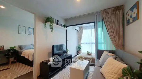 Modern living room with cozy decor and natural light, featuring a sleek TV unit and comfortable seating.