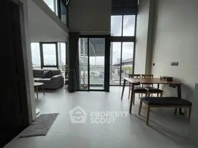 Spacious modern living room with large windows and dining area, offering a bright and airy atmosphere.