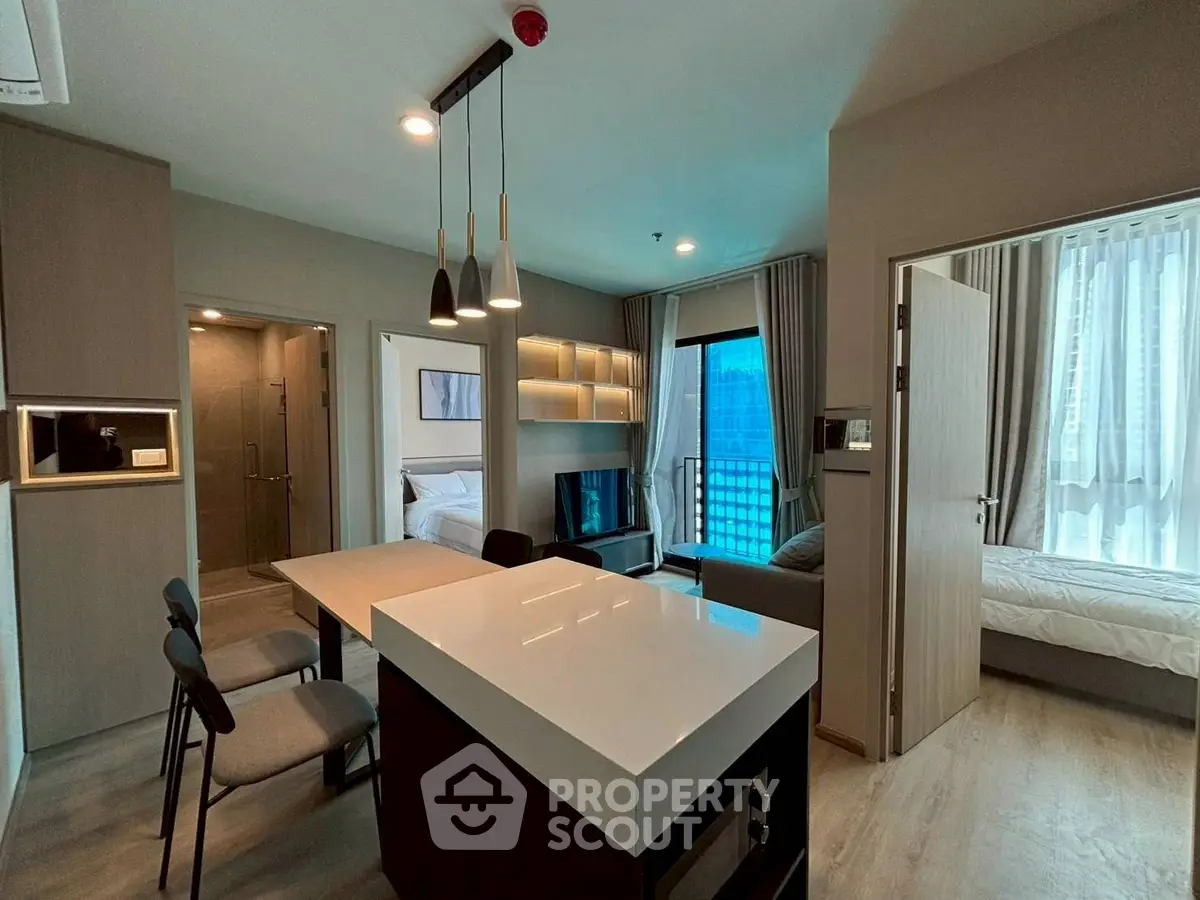 Modern open-plan living room with sleek kitchen and cozy bedroom in a stylish apartment.