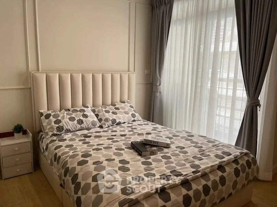 Cozy bedroom with stylish decor and natural light through large windows, perfect for relaxation.