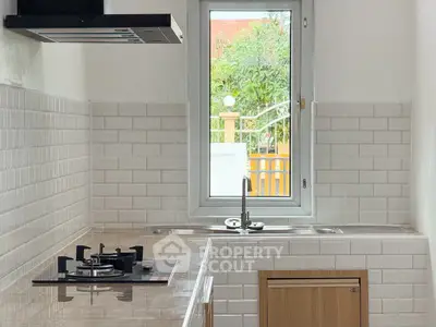 Modern kitchen with gas stove and sleek design, featuring a window view.