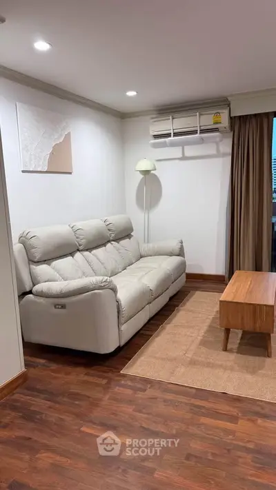 Cozy living room with plush sofa, wooden coffee table, and air conditioning, perfect for relaxation.