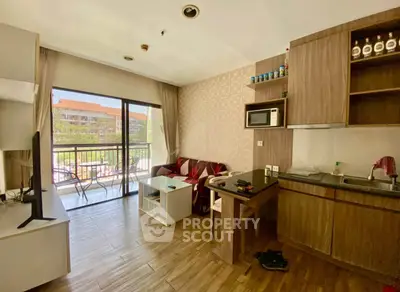 Modern living room with open kitchen and balcony view, featuring stylish wooden flooring and contemporary furniture.
