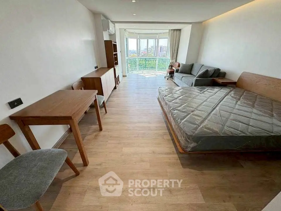 Spacious studio apartment with modern furnishings and large windows offering city views.