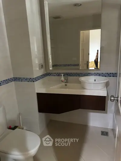 Modern bathroom with sleek fixtures and stylish design, featuring a vessel sink and elegant tile accents.