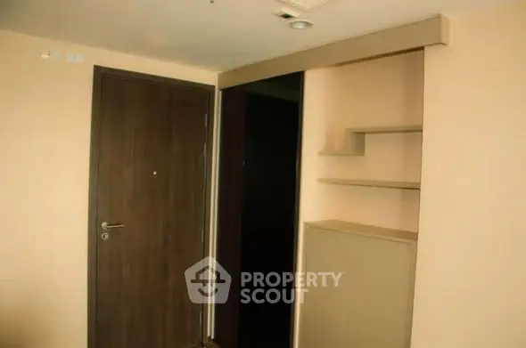 Modern apartment entrance with sleek wooden door and built-in shelving