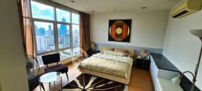 Spacious bedroom with city view, modern decor, and natural light in urban apartment.