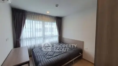 Modern bedroom with large window and stylish furnishings in a contemporary apartment.