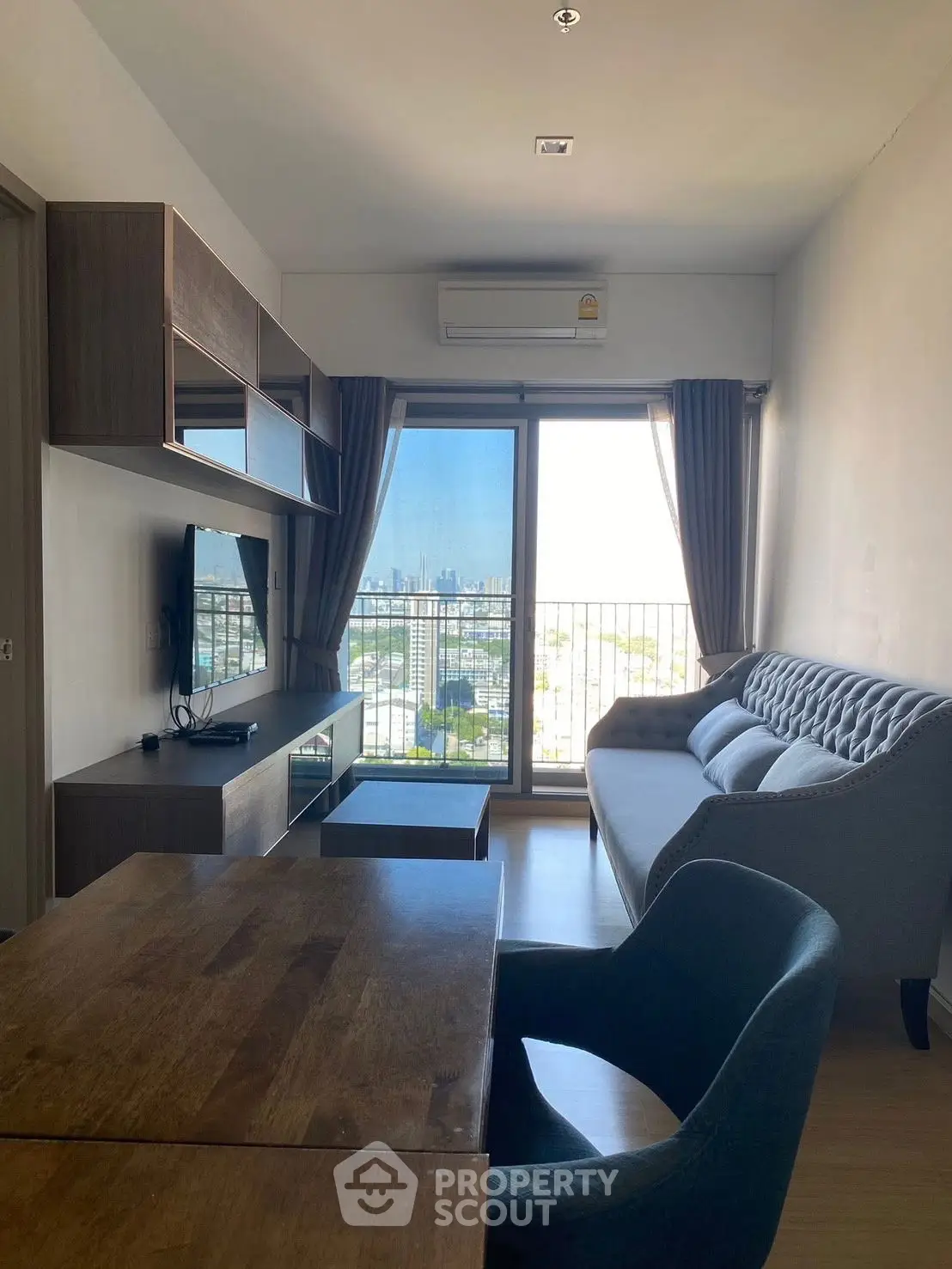 Modern living room with city view, stylish furniture, and natural light.