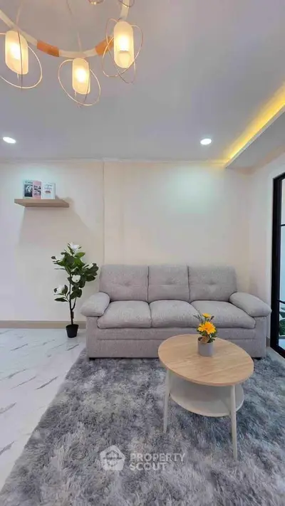 Modern living room with cozy gray sofa, stylish lighting, and elegant decor for a welcoming ambiance.