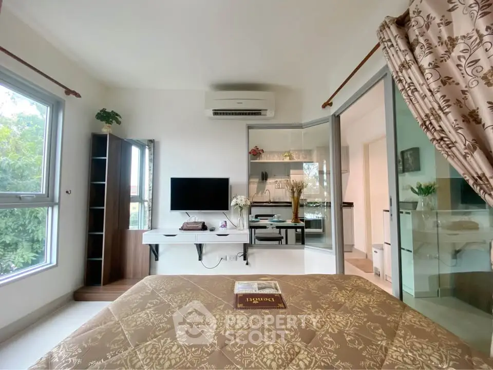 Modern bedroom with TV, air conditioning, and large windows offering natural light.