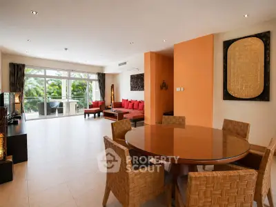 Spacious living room with modern decor and large windows opening to a balcony with lush views.