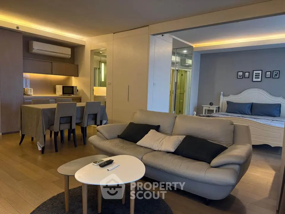 Modern open-plan living room with cozy seating and dining area, featuring stylish lighting and elegant decor.