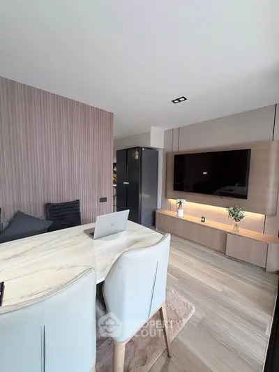 Modern living room with sleek design, featuring a marble dining table, stylish chairs, and a wall-mounted TV.