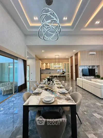 Luxurious open-plan living room with elegant dining area and modern kitchen, featuring stylish lighting and marble flooring.