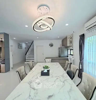 Elegant dining area with marble table and modern chandelier in a stylish home interior.