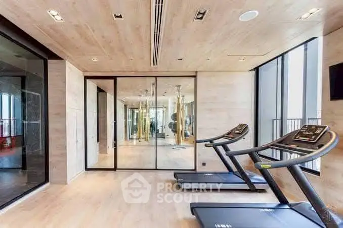Modern gym with treadmills and mirrored walls in luxury apartment building.
