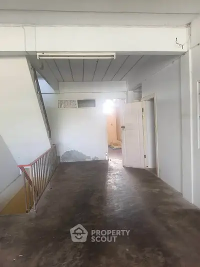 Spacious interior hallway with natural light and open door, ideal for renovation.
