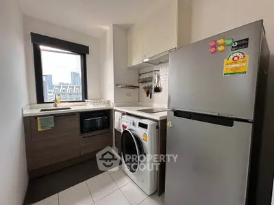 Modern kitchen with sleek appliances and city view, featuring washing machine and fridge.