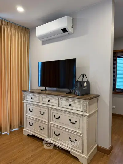 Charming bedroom with elegant dresser and modern TV setup.