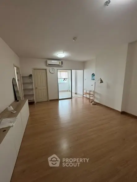 Spacious empty living room with wooden flooring and natural light.