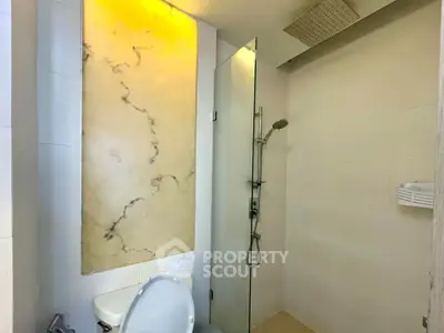 Modern bathroom with elegant marble accent wall and sleek shower design.