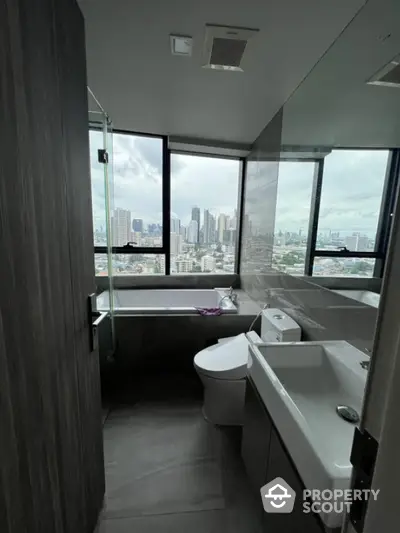 Modern bathroom with city view, featuring sleek fixtures and large windows.