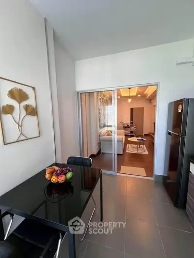 Modern apartment interior with sleek kitchen and dining area, featuring glass doors leading to a cozy living room.