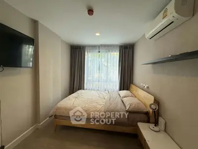 Cozy bedroom with modern decor, featuring a comfortable bed, wall-mounted TV, and air conditioning.