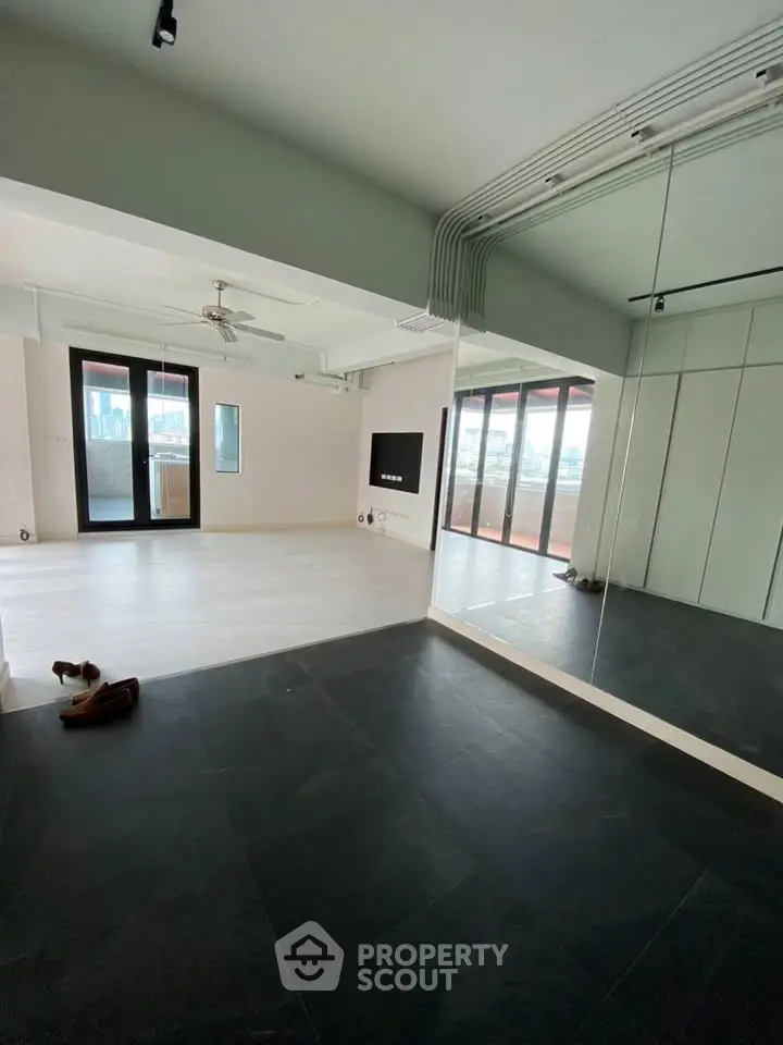 Spacious modern living room with large windows and mirrored wall, perfect for natural light and open feel.