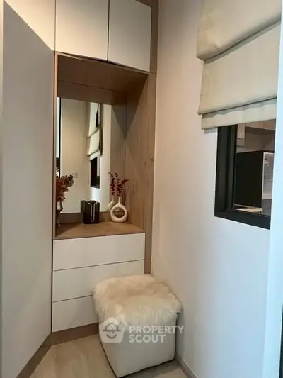Stylish modern storage nook with mirror and plush seating in contemporary home.