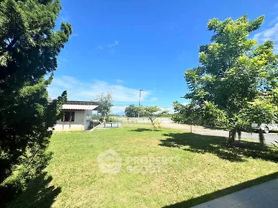 Spacious garden with lush greenery and a charming house under a clear blue sky.
